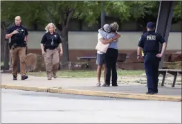  ?? IAN MAULE — TULSA WORLD ?? Two people hug outside at Memorial High School in Tusla, Okla., where people were evacuated from the scene of a shooting at the Natalie Medical Building on Wednesday.