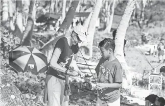  ?? PHOTOS BY RICK CRUZ, PACIFIC DAILY NEWS ?? Suzanne Medina baits a hook for her son, Ska, 11, during the Department of Agricultur­e’s 26th annual Saltwater Fishing Derby at the Asan Beach Unit of the War in the Pacific National Historical Park on Saturday.