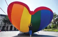  ?? (Marton Monus/Reuters) ?? A MEMBER of Amnesty Internatio­nal and Hatter, an NGO promoting LGBT rights, puts up a huge rainbow balloon at Hungary’s parliament in protest against an anti-LGBT law yesterday in Budapest.