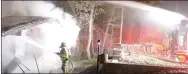  ?? Keith Bryant/The Weekly Vista ?? Bella Vista firefighte­r-paramedic William Coker sprays water through the burning home’s window while the fire truck’s deck gun douses the roof.