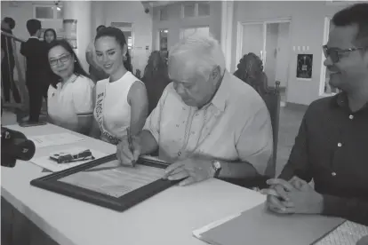  ?? (Photo courtesy of the City Informatio­n Office) ?? Miss Universe Philippine­s 2018 Catriona Gray (2nd from left, seated), Puerto Princesa City Mayor Lucilo Bayron, and UNAIDS Country Director Dr. Louie Ocampo during the signing of the “Fast-Track – Ending the AIDS Epidemic by 2030“commitment on Monday, September 18, at the City Hall.