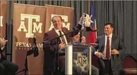  ?? SUZANNE HALLIBURTO­N / AMERICAN-STATESMAN ?? Jimbo Fisher accepts a pair of maroon and white boots after he’s introduced Monday as Texas A&M’s new head football coach.
