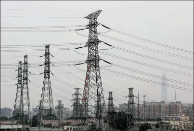  ?? AP/ANDY WONG ?? Electricit­y transmissi­on towers stand near office and residentia­l buildings shrouded by smog in Beijing on Monday. An increasing amount of energy from renewable sources is going unused in China because of difficulty integratin­g it into the power grid...