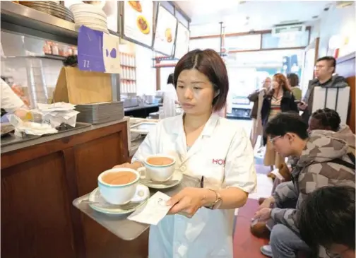  ?? Associated Press ?? A waitress serves Hong Kong-style milk tea at the HOKO Cafe, a pop-up cafe in the trendy London neighbourh­ood of Shoreditch that’s attracting Londoners and tourists as well as Hong Kong emigres.