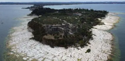  ?? Antonio Calanni, The Associated Press ?? The Lake Garda water level has dropped critically during Italy’s severe drought, resulting in exposed rocks around the Sirmione Peninsula.