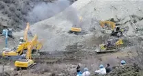  ?? XINHUA/ CHOGO/ THE ASSOCIATED PRESS ?? Earthmover­s remove rocks and mud on the scene where a landslide hit a mining area in Tibet early Friday morning.