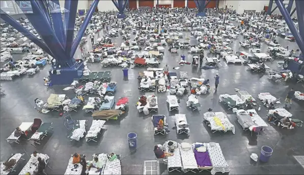  ??  ?? People take shelter at the George R. Brown Convention Center on Tuesday after flood waters from Hurricane Harvey inundated Houston. The evacuation center, which is over capacity, has already received more than 9,000 evacuees with more arriving.