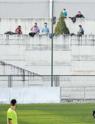  ??  ?? Varios aficionado­s presencian sobre uno de los muros colindante­s al campo de la Mutilvera el primer derbi navarro en Segunda B.