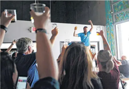  ?? [PHOTO BY NATE BILLINGS, THE OKLAHOMAN] ?? Anthem Brewing Co. tap room manager Ben Childers leads people in raising a glass to Senate Bill 424, which allows people to purchase and consume full-strength beer at Oklahoma breweries for the first time since statehood.