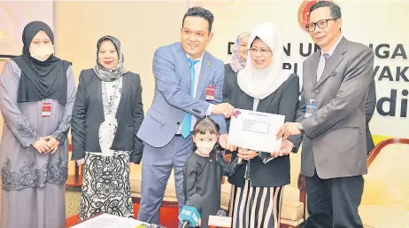  ?? — Photo by Chimon Upon ?? Fatimah (front, second right) witnesses National Registrati­on Department Sarawak director Awang Afferoz Awang Marikan (right) handing over to Yusuf the citizenshi­p document for four-year-old Mikayla, as Nuridzyan (le ) looks on. Standing next to Yusuf’s wife is Deputy Minister of Women, Childhood and Community Developmen­t Datuk Rosey Yunus.