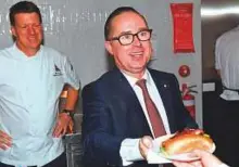  ?? AFP ?? ■ Alan Joyce serves a sausage roll during the opening of the new transit lounge at Perth Airport in Australia.