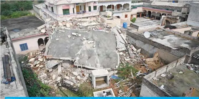  ?? — AFP ?? MIRPUR: Pakistani residents look at a collapsed house in an earthquake-hit area on the outskirts of Mirpur in Pakistan-controlled Kashmir yesterday.