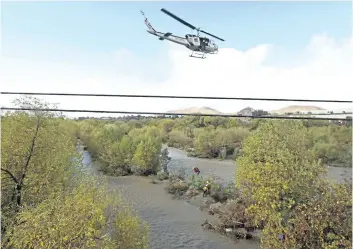  ?? STAN LIM/THE ASSOCIATED PRESS ?? A women is hoisted out with the help of a San Bernardino County Sheriff’s helicopter on Tuesday, in the Santa Ana River and near the borders of Rialto, Colton, and Riverside, Calif.