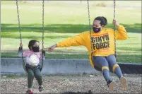  ?? CHRIS RILEY — TIMES-HERALD ?? Tranica Swindle reaches out to tough her daughter Rini, 2, as they swing at the Blue Rock Springs playground in Vallejo. California officials updated the state’s COVID-19 guidelines, on Wednesday, deeming playground­s to be essential and allowing them to remain open.