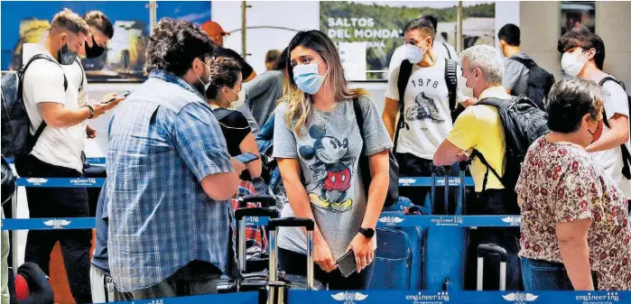  ?? AP ?? Pasajeros con tapabocas en un aeropuerto en espera de documentar su equipaje.