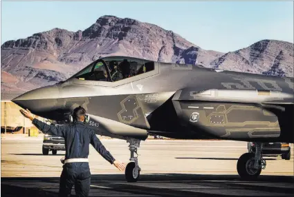  ?? JEFF SCHEID/ LAS VEGAS REVIEW-JOURNAL FILE ?? A worker directs an F-35 Lightning II, piloted by Capt. Brent Golden, at Nellis Air Force Base in January. The base received its first F-35 joint strike fighter that month. The aircraft is the U.S. military’s most expensive weapons system.