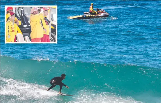  ?? Picture: Jason O'Brien ?? A surfer rides a wave at Burleigh Heads as a lifeguard patrols on a jetski after a recent run of shark sightings on the Gold Coast.