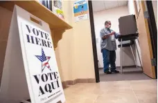  ??  ?? George Maestas, with the Rio Arriba County Clerk’s Office, disinfects a used voting booth at an early voting location in Tierra Amarilla.