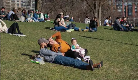  ?? AMaNDa saBga pHOTOs / BOsTON HEraLD ?? SOAKING IN THE SUN: Juliana Teixiera and Felipe Rodrigues, of Brazil, with their daughter Ayla, laugh as they sit in Boston Common on Sunday. Below, a person sits near the empty Public Garden pond.