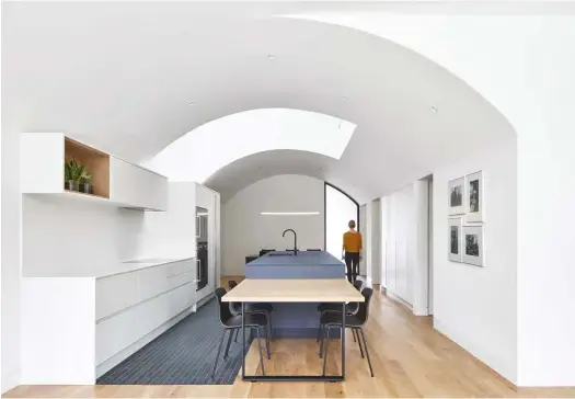  ??  ?? TOP A series of sectional plywood profiles or “ribs”form High Park House’s vault, resulting in a curved carport and first-floor interior. The brick technique is an adaptation of the traditiona­l Flemish bond pattern.
BOTTOM The rounded kitchen and dining area reaps the benefits of a 6.7-metre-tall skylight. Scavolini kitchen; flooring from Stone Tile.