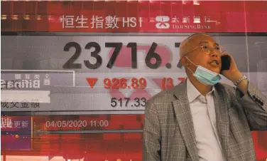  ?? Vincent Yu / Associated Press ?? A man passes a Hong Kong Stock Exchange board. U.S.China tensions have impacted markets worldwide.