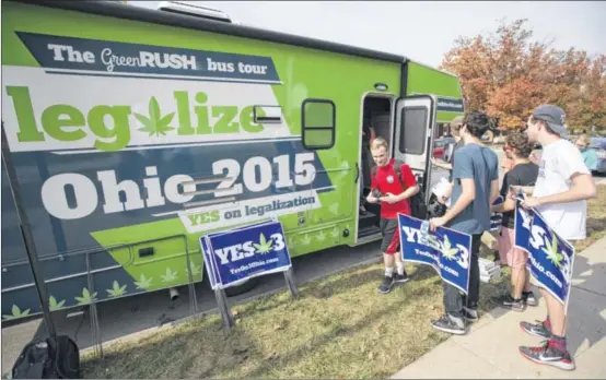  ?? JOHN MINCHILLO / AP ?? College students collect lawn signs and shirts at a promotiona­l tour bus from Responsibl­eOhio, a pro-marijuana legalizati­on group, at Miami University, in Oxford, Ohio, in October. Voters turned away the legalizati­on effort for both medical and...