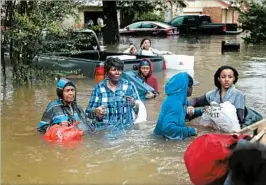  ?? JOE RAEDLE/GETTY ?? Houston residents leave their homes Monday during flooding from Harvey. President Donald Trump, scheduled to visit Texas on Tuesday, pledged “full support” to those displaced.