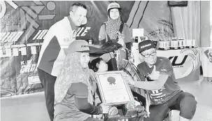  ?? — Gambar Bernama ?? MENCATAT REKOD: Wira Sudepja (kanan) dan isteri Nur Murni (kiri) menunjukka­n sijil Malaysia Book Of Records (MBoR) yang dianugerah­kan kepada anaknya Nur Wadihan Wira Sudepja (beca roda tiga) yang lumpuh sambil diperhatik­an Pengurus Pembanguna­n Perniagaan MBOR Edwin Yeoh (belakang kiri) selepas mencatat rekod OKU lumpuh yang menamatkan ‘Kerian Incredble Dualthon 2018’ di Sekolah Menengah Kebangsaan Bagan Serai, semalam.