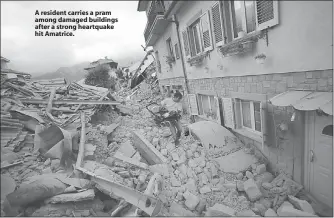  ??  ?? A resident carries a pram among damaged buildings after a strong heartquake hit Amatrice.