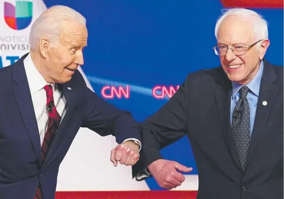  ??  ?? Joe Biden and Bernie Sanders greet each other with a safe elbow bump before the start of the latest Democratic presidenti­al debate Picture: AFP