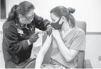  ?? BRYAN ANSELM/THE NEW YORK TIMES ?? A medical worker receives one of the first Moderna COVID-19 vaccine doses administer­ed at Christ Hospital in Jersey City on Dec. 21.