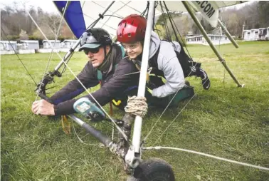  ?? STAFF PHOTO BY DOUG STRICKLAND ?? Flight instructor Dave Miller, left, talks with tandem hang-gliding passenger Mia Audier before the two are towed into the air by an airplane from the Lookout Mountain Flight Park on March 16.