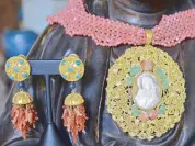  ??  ?? Gold- plated granulated silver earrings set with turquoise, lapis lazuli and coral branches are paired with oversized cameo pendant, set with antique and vintage tambourine, coral flowers and jade leaves and strung on a necklace of fabric-like woven...