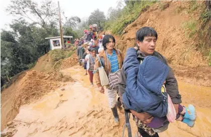  ?? Photo / AP ?? Residents of Itogon make their way to safety after mudslides buried dozens in the town.