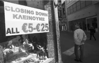  ??  ?? UNA TIENDA anuncia descuentos en su clausura en una céntrica calle de Nicosia, la capital de Chipre.
