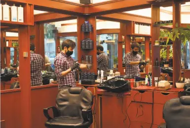  ?? Photos by Paul Kuroda / Special to The Chronicle ?? Iggy Ibrahimli prepares for customers inside Ahmet’s Barber & Hair Styling on California Street for the first time since the midMarch closure order. Businesses like hair salons reopened outdoors a few days earlier.