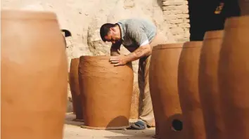  ?? AFP ?? A potter gives finishing touches to a clay pot in Najaf. Pottery has deep roots in Iraq, where ancient civilisati­ons turned to clay to build their homes, shape their cooking utensils, and even make their ovens.