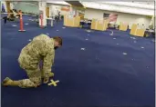  ?? DAVID GOLDMAN — AP FILE ?? Rhode Island Army National Guard Staff Sgt. Andrew Bates pulls up tape marking a line at a coronaviru­s mass-vaccinatio­n site at the former Citizens Bank headquarte­rs in Cranston, R.I., on June 10, 2021.