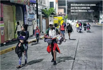  ?? IMAGES /GETTY ?? Hondureños a su paso por la localida deIsla en México.