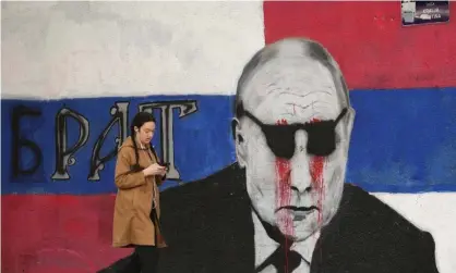  ?? ?? A woman passes a vandalised mural of Vladimir Putin in Belgrade, Serbia. Photograph: Darko Vojinović/AP