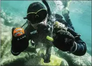  ?? LUDOVIC FEKETE — CLEAN UP THE LAKE VIA AP ?? CUTL diver Colin West shows debris found in the lake from an initial dive in 2020, at Lake Tahoe, Nev. They found no trace of a mythical sea monster, no sign of mobsters in cement shoes or long-lost treasure chests. But scuba divers who spent the past year cleaning up Lake Tahoe’s entire 72-mile shoreline have come away with what they hope will prove much more valuable: tons and tons of trash.