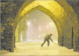  ?? Matthias Bein The Associated Press ?? A man shovels snow under an archway early Sunday in Wernigerod­e, Germany.