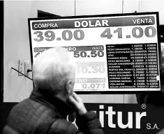  ?? — Reuters photo ?? A man looks at a currency exchange board in Buenos Aires’ financial district, Argentina. Argentina’s Central Bank hiked its benchmark interest rate from 45 to 60 per cent in a dramatic but fruitless bid to shore up the peso, which plunged to a record low against the dollar.
