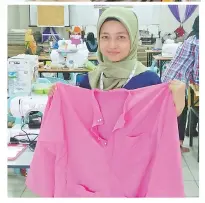  ??  ?? DG. SYARMI Eryani menunjukka­n hasil jahitan baju Melayu yang telah siap dijahit dengan cantik dan bermutu.