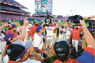  ?? ?? The Philadelph­ia Phillies celebrate their victory over the Atlanta Braves on Saturday in Philadelph­ia. The Phillies won, 8-3.