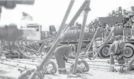  ?? James Durbin / Midland Reporter-Telegram file ?? Halliburto­n employees work on high-pressure pipes supplying a hydraulic fracturing site managed by Octane Energy near Stanton in West Texas.