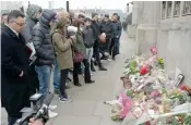  ?? — AP ?? People stand in front of floral tributes to victims of Wednesday’s attack outside the Houses of Parliament in London on Friday.