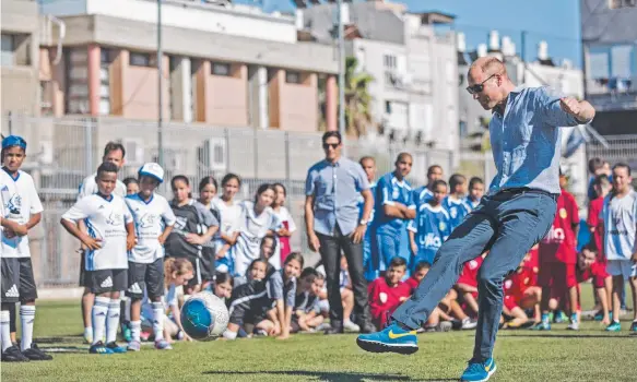  ?? Picture: AFP ?? Prince William puts boot to ball as he meets with Jewish and Arab children at the Neve Golan Stadium in the Israeli city of Jaffa on Tuesday.