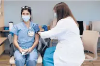  ?? DEREK DAVIS/PORTLAND PRESS HERALD ?? Nurse Kayla Mitchell, left, of Maine Medical Center’s COVID ICU unit is the first person in the state to receive the Pfizer-BioNTech COVID-19 vaccine Tuesday in Portland, Maine.