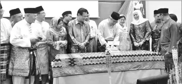  ??  ?? Awang Tengah cuts a Raya cake and later gives a piece to his wife Dayang Morliah while others look on.